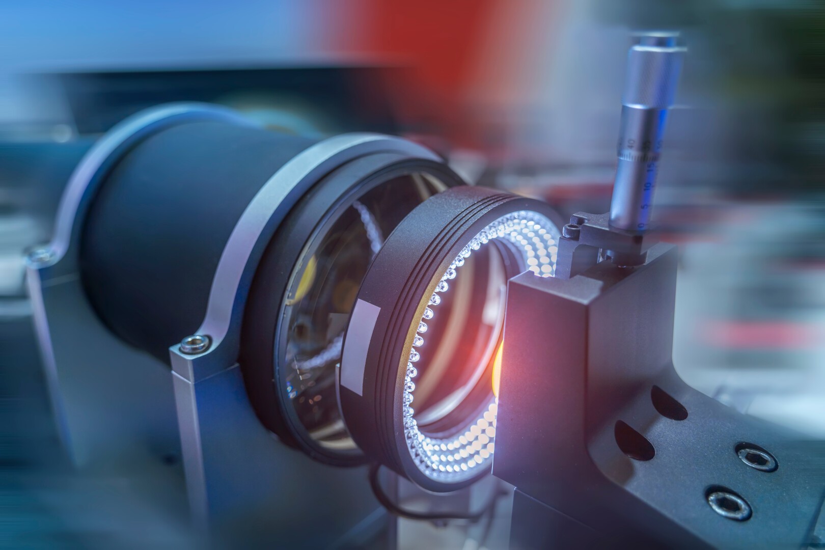 Close-up of a precision optical device or machine vision system with a lens, illuminated ring light, and a measurement probe, used for industrial inspection or scientific research.